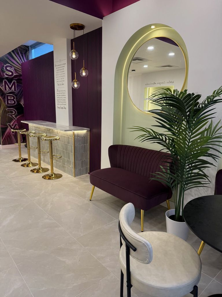 The bar with gold stools, the lettering wall and an arch with a round mirror.