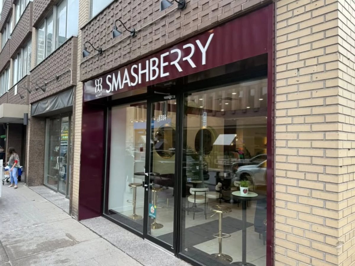 The Smashberry storefront at 1314 Greene Avenue by day: burgundy sign on the brick façade, gold stools behind the window.