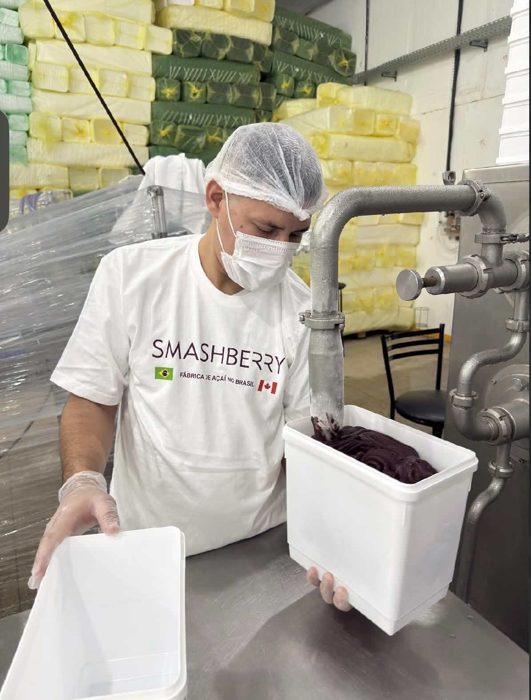 La pulpe d’açaí, épaisse et violette, coule de la machine dans un bac blanc.