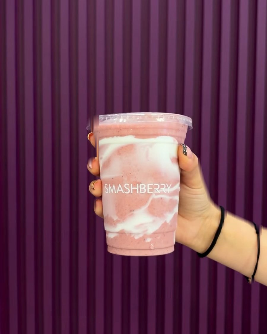 Recovery Lab smoothie, strawberry pink swirled with white, held in front of the fluted wall.