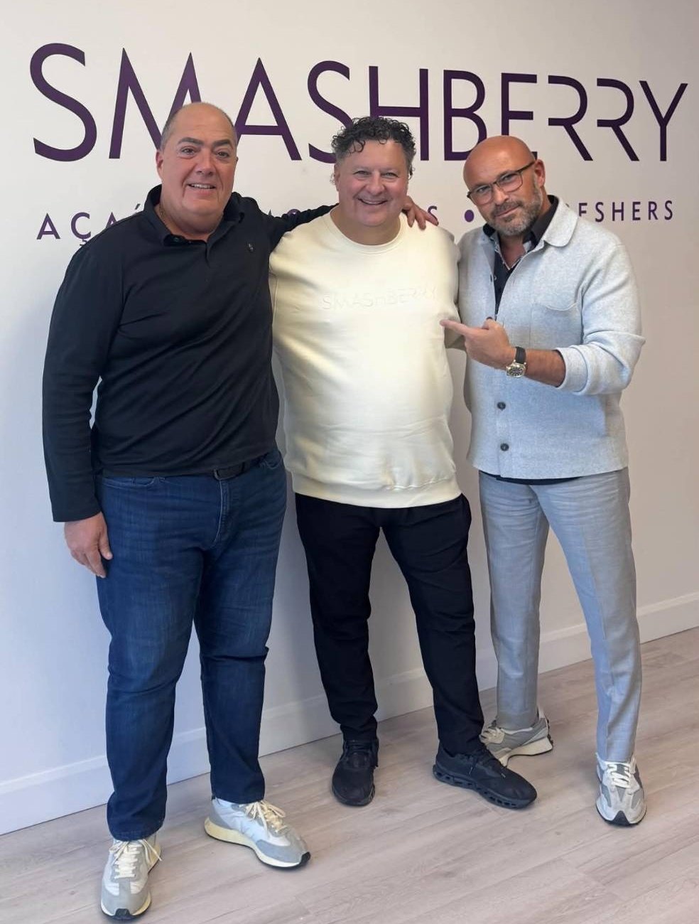 Tony Marinaro and the Smashberry team, smiling in front of the Smashberry logo wall.